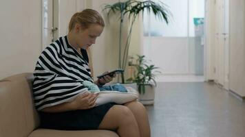 Woman using mobile and nursing baby in child health center video