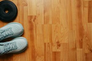 New female running shoes and weight plate on wooden floor photo