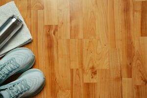 New female running shoes water bottle and towel on wooden floor photo