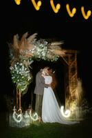 bride and groom against the backdrop of an evening wedding arch photo