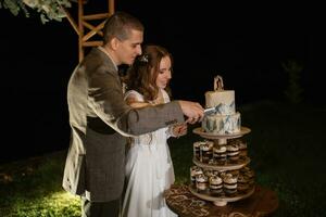 los recién casados felizmente cortan y prueban el pastel de bodas foto