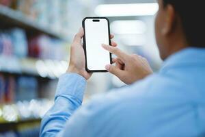 Supermarket Store, Handsome young man uses his smartphone and checks the products and products he wants to buy in the supermarket. photo