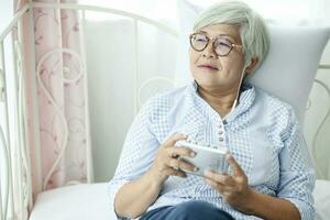 The elderly women wear blue clothes, wear glasses, sit happily in the house. photo