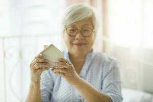 The elderly women wear blue clothes, wear glasses, sit happily in the house. photo