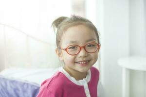 un asiático niña vistiendo lentes es sonriente felizmente. foto
