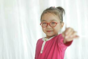 un asiático niña vistiendo lentes es sonriente felizmente. foto