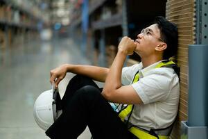 An Asian warehouse worker who is tired from work. Getting fired from a job. Unemployed. Failed. Desperate. photo