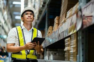 asian male warehouse worker wearing a safety vest working in a warehouse. photo