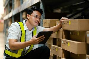 A warehouse worker uses a laptop to check the boxes in a warehouse warehouse full of boxes. Industrial Warehouse. photo