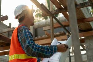 inspector or engineer is inspecting construction and quality assurance new house using a blue print. Engineer or architects or contactor work to build the house before handing it over to the homeowner photo
