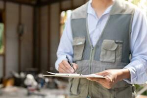 el inspector o ingeniero está inspeccionando la construcción y el aseguramiento de la calidad de la nueva casa usando una lista de verificación. ingenieros o arquitectos o contratistas trabajan para construir la casa antes de entregársela al propietario foto