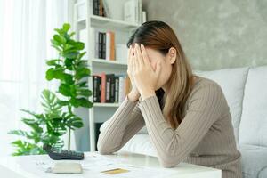 Stressed and headache asian woman with large bills or invoices no money to pay to expenses and credit card debt. shortage, Financial problems, mortgage, loan, bankruptcy, bankrupt, poor, empty wallet photo