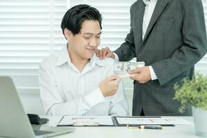 los empresarios reciben salarios o bonificaciones de la gerencia o del jefe. empresa dar recompensas para fomentar el trabajo. hombre de negocios sonriente disfrutando de una recompensa en el escritorio de la oficina. foto