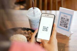 mujer utilizar teléfono inteligente a escanear qr código para orden menú en café restaurante con un digital entrega. escoger menú y orden acumular descuento. mi billetera, tecnología, pagar en línea, crédito tarjeta, banco aplicación foto