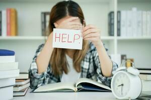 Asian student woman have anxiety because of exams, female prepare for test and learning lessons in the library. stress, despair, haste, misunderstanding reading, discouraged, expectation, knowledge photo