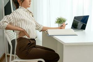 woman holding her lower back while and suffer from unbearable pain health and problems, chronic back pain, backache in office syndrome, scoliosis, herniated disc, muscle inflammation photo