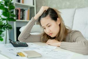 Stressed and headache asian woman with large bills or invoices no money to pay to expenses and credit card debt. shortage, Financial problems, mortgage, loan, bankruptcy, bankrupt, poor, empty wallet photo