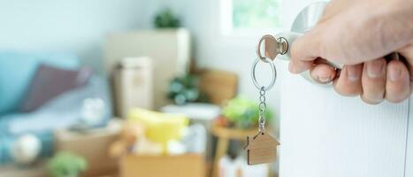 Moving house, relocation. The key was inserted into the door of the new house, inside the room was a cardboard box containing personal belongings and furniture. move in the apartment, banner photo