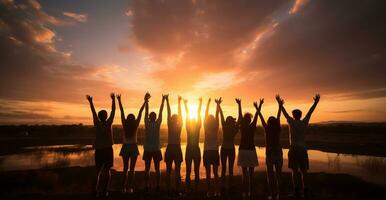 Silhouette of a group of friends standing on top of a mountain and looking at the sunset AI Generated photo