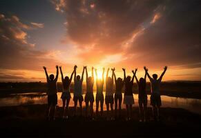 silueta de un grupo de amigos en pie en parte superior de un montaña y mirando a el puesta de sol ai generado foto