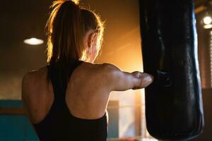 mujer yo defensa niña fuerza. fuerte mujer combatiente formación puñetazos en boxeo anillo. sano fuerte niña puñetazos boxeo bolsa. formación día en boxeo gimnasia. fuerza ajuste cuerpo rutina de ejercicio capacitación. foto