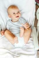 Cute little newborn girl with smiling face looking at camera on white background. Infant baby resting playing lying down on feeding chair at home. Motherhood happy child concept. photo