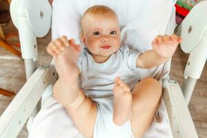 Cute little newborn girl with smiling face looking at camera on white background. Infant baby resting playing lying down on feeding chair at home. Motherhood happy child concept. photo