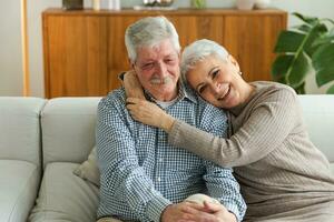 Senior adult mature couple hugging at home. Mid age old husband and wife embracing with tenderness love enjoying sweet bonding wellbeing. Grandmother grandfather together. Family moment love and care. photo