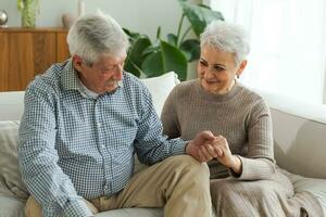 Senior adult mature couple in love holding hands at home. Mid age old husband and wife looking with tenderness love enjoying wellbeing. Grandmother grandfather together. Family moment love and care. photo