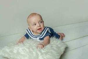 Infant baby boy lies on pillow on white bedroom background photo
