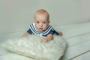 Infant baby boy lies on pillow on white bedroom background photo