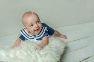 Infant baby boy lies on pillow on white bedroom background photo