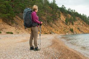 excursionismo turismo aventura. mochilero caminante mujer mirando a hermosa vista. caminante niña dama turista con mochila caminando cerca lago. joven contento mujer disfrutar caminata trekking turismo activo vacaciones. foto