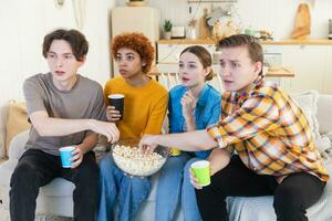 Group of friends watching sport match soccer football game on tv. Happy football fans celebrating victory at home. Friendship sports entertainment concept. Diverse buddies having fun together at home. photo