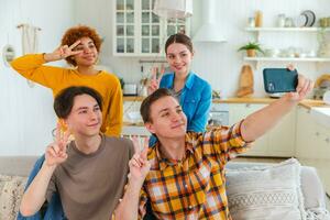 Cheers Funky mood. Happy group of friends make selfie. Man taking photo of friends at party. Group of multiracial young people taking photo on phone. Young people enjoy their company smile have fun.