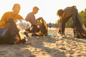 Earth day. Volunteers activists team collects garbage cleaning of beach coastal zone. Group of people puts plastic trash in garbage bags on ocean shore. Environmental conservation. photo