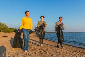 tierra día. voluntarios activistas recoge basura limpieza de playa costero zona. mujer mans con basura en basura bolso en Oceano costa. ambiental conservación costero zona limpieza. borroso video. foto