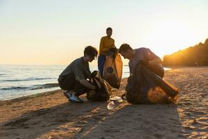 Earth day. Volunteers activists collects garbage cleaning of beach coastal zone. Woman and mans puts plastic trash in garbage bag on ocean shore. Environmental conservation coastal zone cleaning. photo