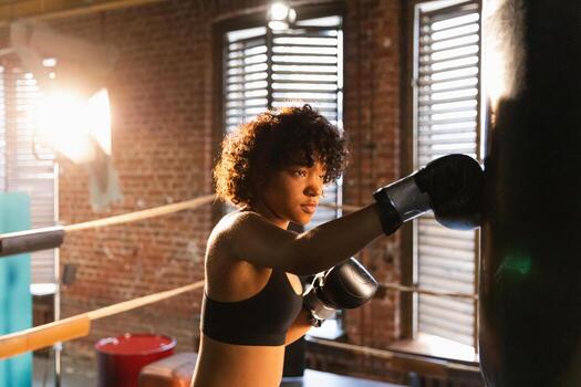 mujer yo defensa niña fuerza. africano americano mujer combatiente formación puñetazos en boxeo anillo. sano fuerte niña puñetazos boxeo bolsa. formación día en boxeo gimnasia. fuerza ajuste cuerpo rutina de ejercicio capacitación. foto