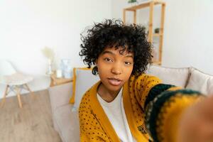 Happy african american teen girl blogger smiling face talking to webcam recording vlog. Social media influencer woman streaming making video call at home. Headshot portrait selfie webcamera view. photo