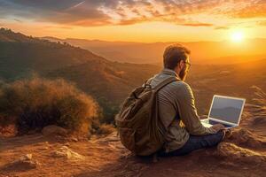 Digital nomad sitting on top of a hill working with his laptop over the city at sunset ,Generative AI. photo