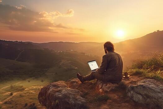 Digital nomad sitting on top of a hill working with his laptop over the city at sunset ,Generative AI. photo
