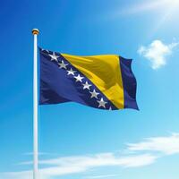 Waving flag of Bosnia on flagpole with sky background. photo