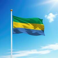 Waving flag of Gabon on flagpole with sky background. photo