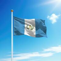 Waving flag of Guatemala on flagpole with sky background. photo