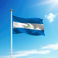 Waving flag of Nicaragua on flagpole with sky background. photo