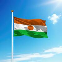 Waving flag of Niger on flagpole with sky background. photo