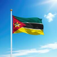 Waving flag of Mozambique on flagpole with sky background. photo