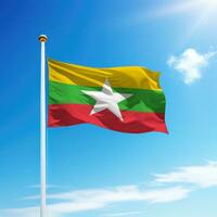 Waving flag of Myanmar on flagpole with sky background. photo