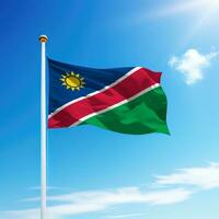 Waving flag of Namibia on flagpole with sky background. photo